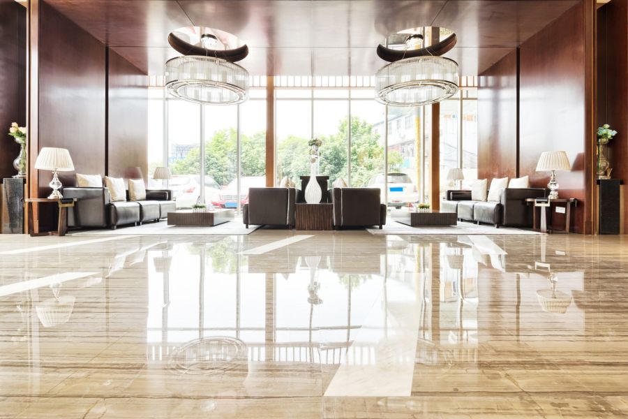 Polished hotel lobby with shiny marble floors, sofas, lamps and large windows